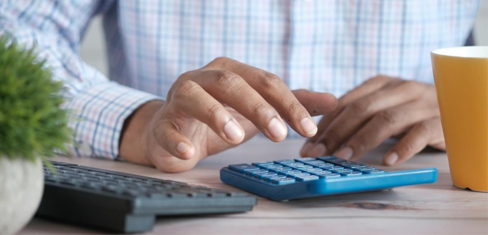 Manos sobre una calculadora y un teclado, llevando las cuentas