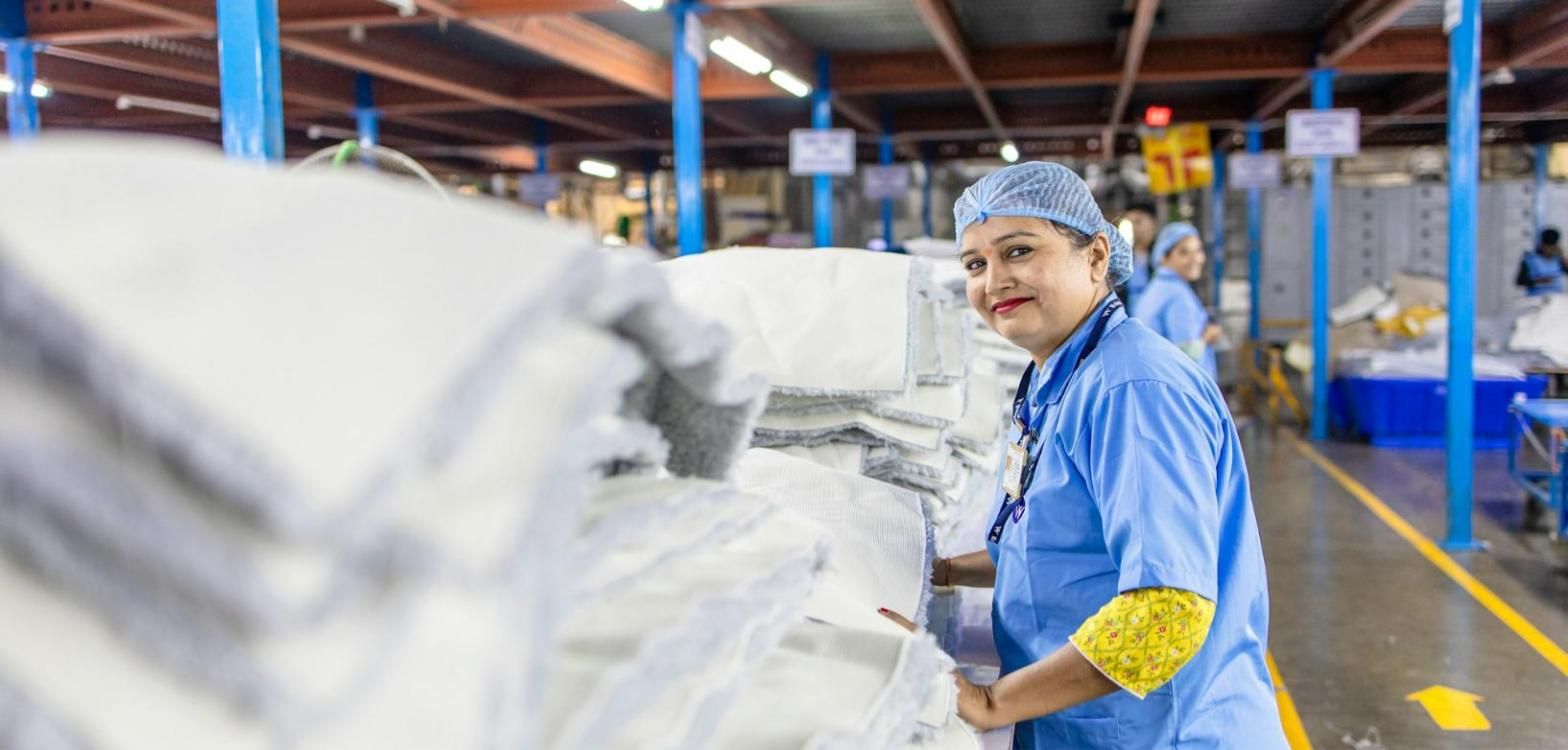 Operaria sonriente revisando el material en una nave de producción