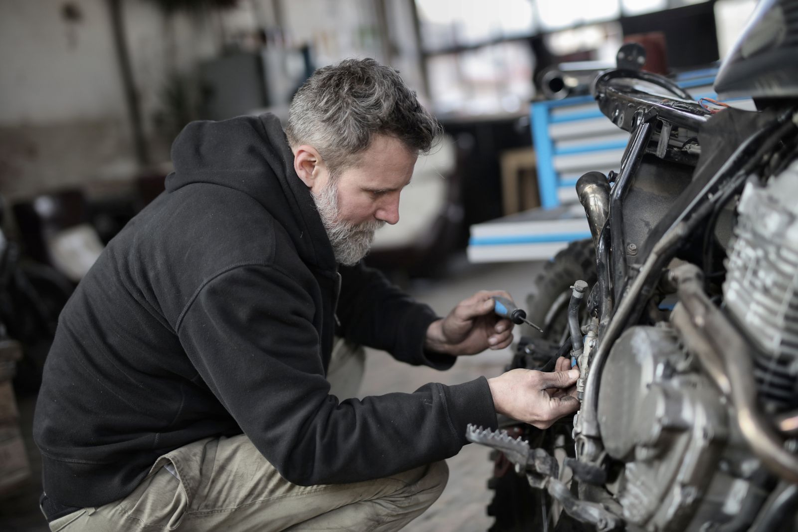Mecánico con barba reparando el motor de una moto en un taller